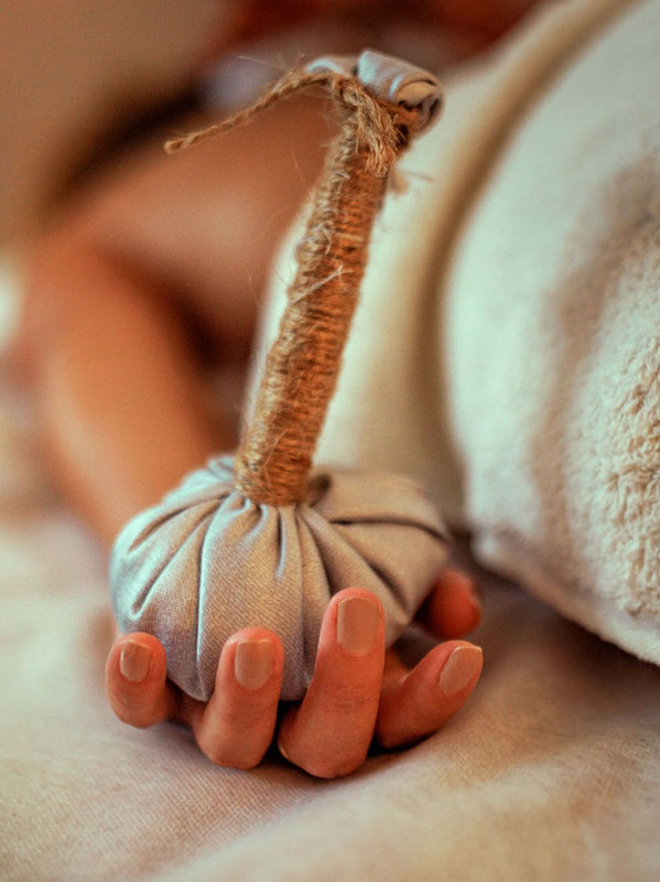 Hot herbal ball spa massage body treatment, woman holding bag in hand